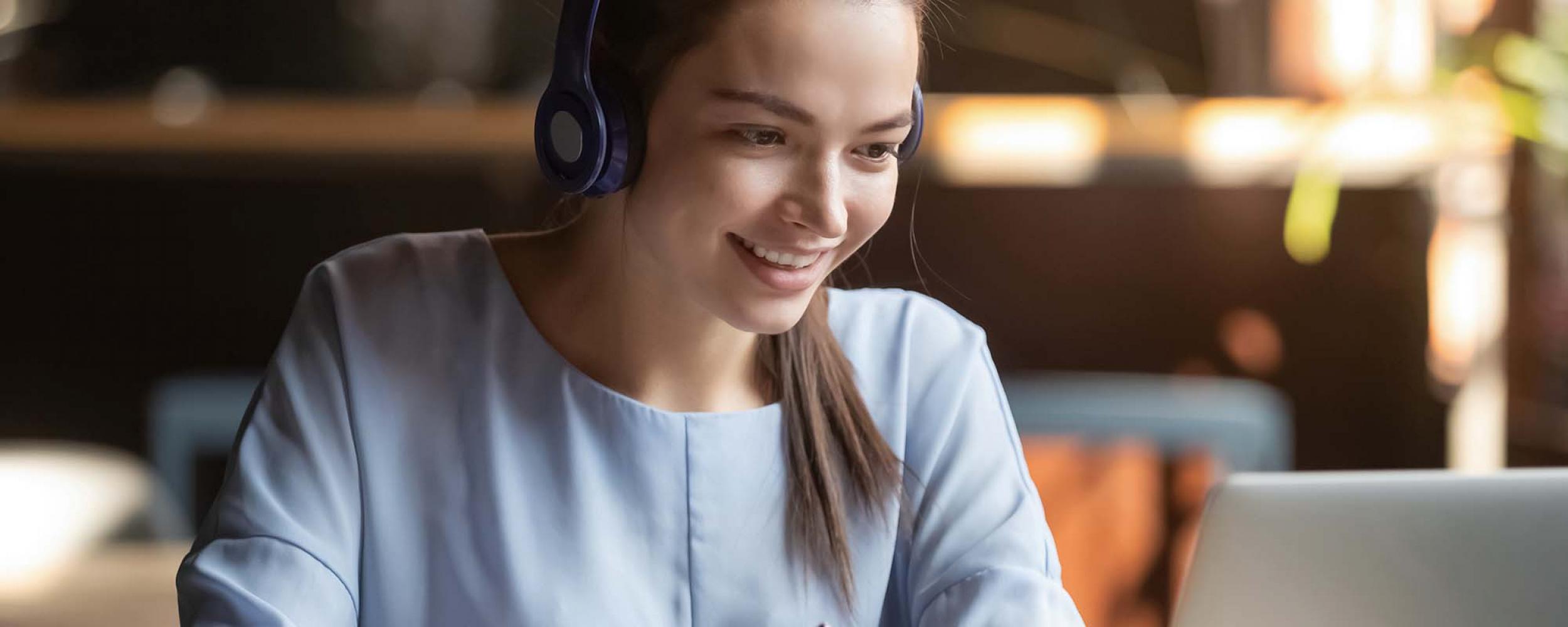 Junge Frau mit Kopfhörern vor Laptop